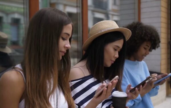 3 young beautiful girls browsing social media on their smartphones