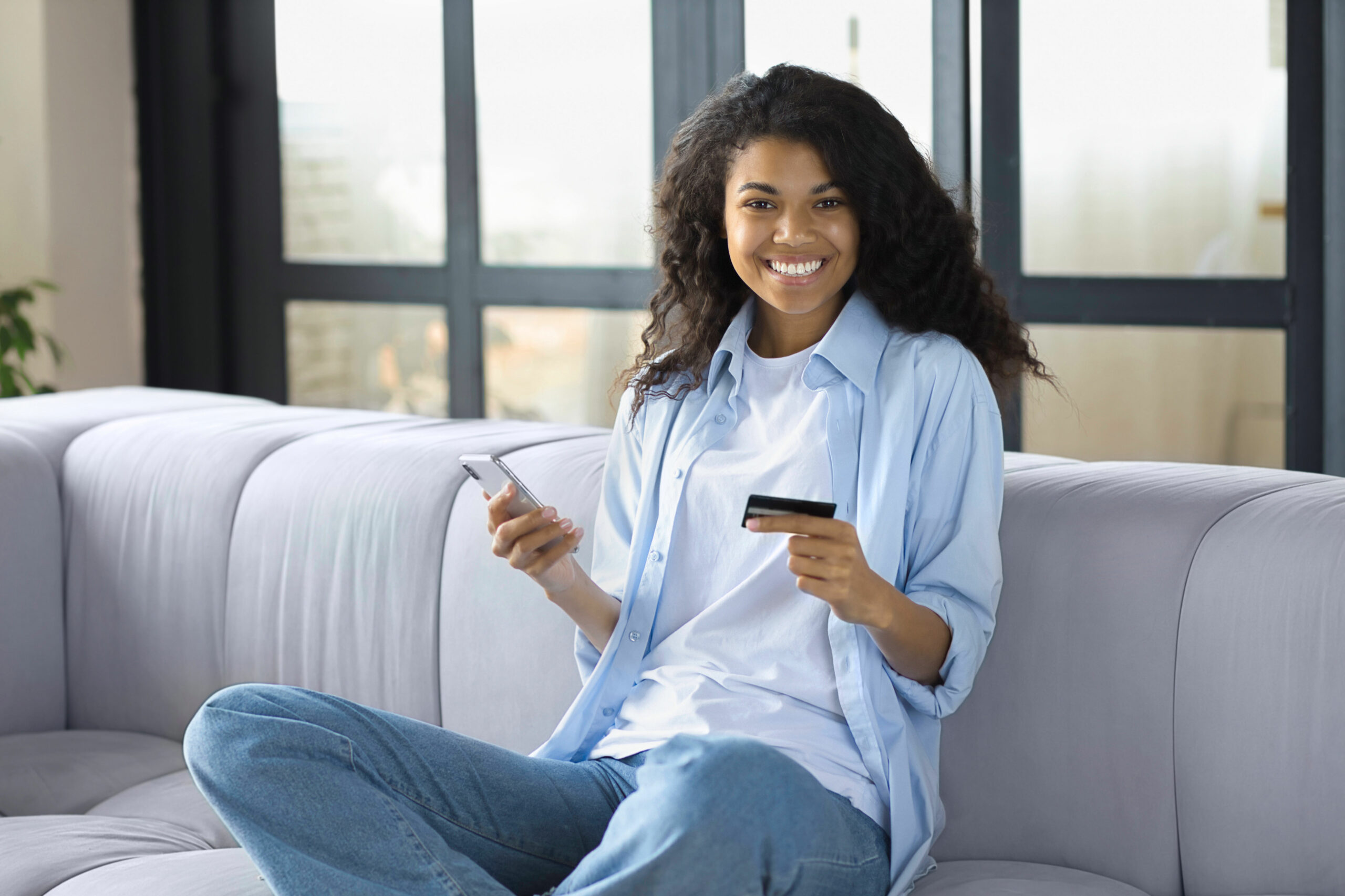 Happy Young African American Woman Holding a smartphone and a bank card