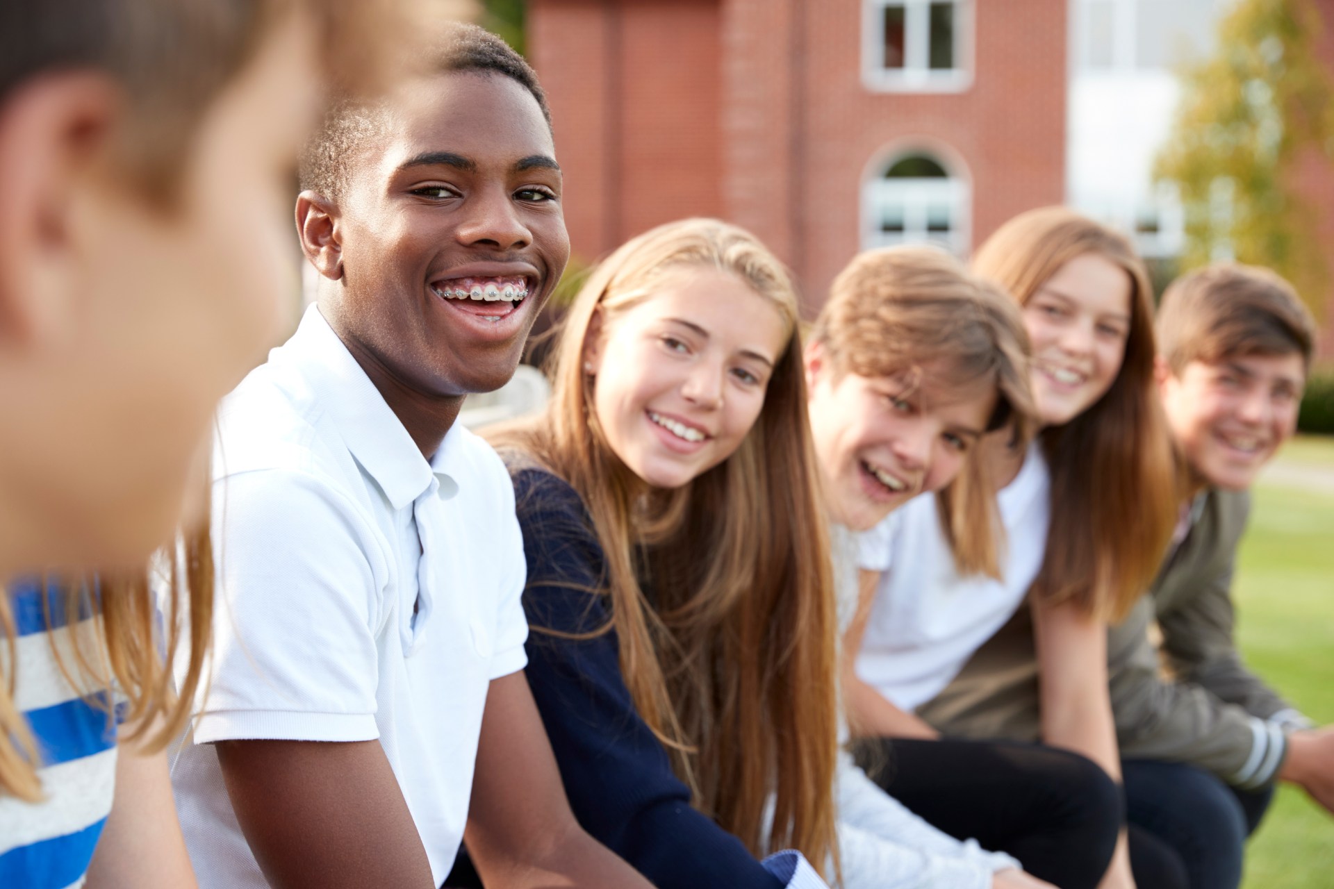 Group Of Teenage Students Sitting Outside School Buildings